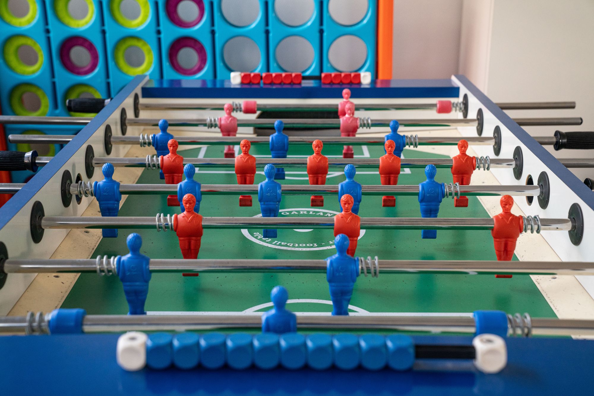 Ein Tischkicker steht im Raum und man sieht rote und blaue Spielfiguren