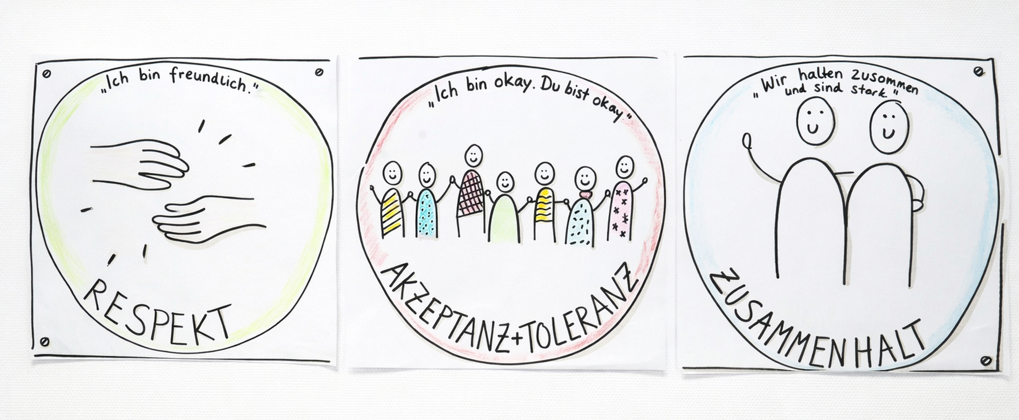 3 Zeichnungen mit Filzstift hängen an der Wand zu den Themen Respekt Akzeptanz Toleranz Zusammenhalt